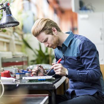 A guy working on a circuit board and concentrating on it