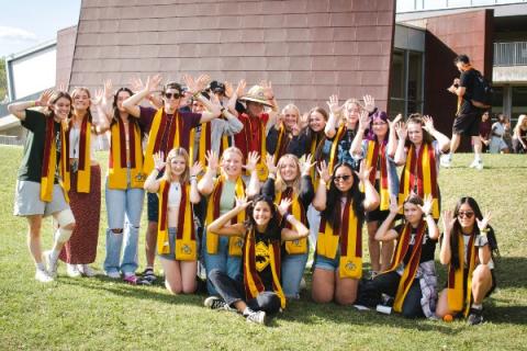 A group of Gzowski students wearing scarves and making moose antlers with their fingers.