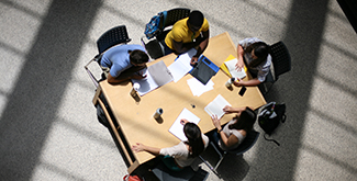 3 Students studying at a table on the second floor of the library, bird's-eye angle
