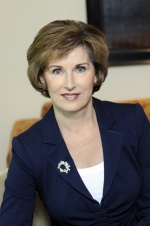 Head and shoulders photo of Kathleen Taylor smiling at the camera wearing a blue blazer and white t-shirt