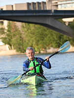 Dr. Leo Groarke kayaking under bridge at Peterborough campus.