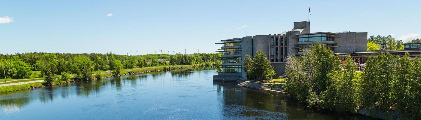 Picture of the west bank of campus from across the Otonabee river during the summer