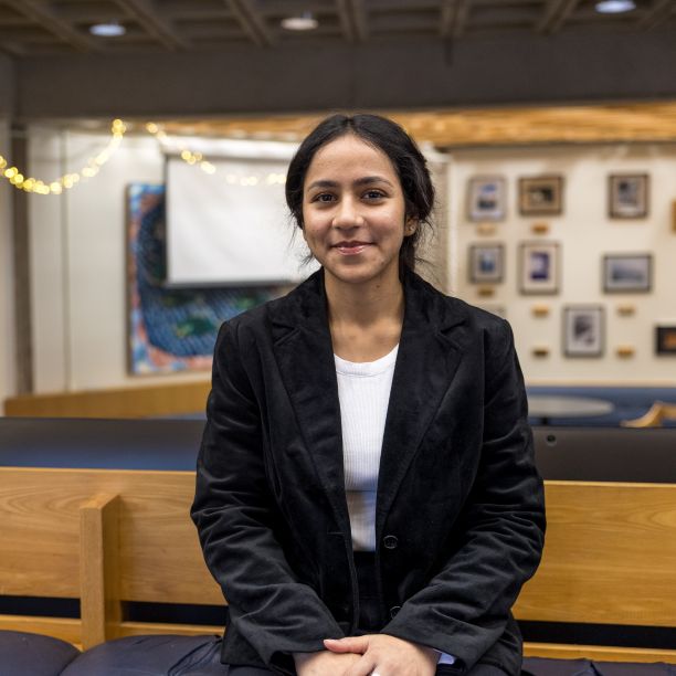 Tamanna, a transfer student, seated on a wooden bench in a student space on Trent’s Campus 