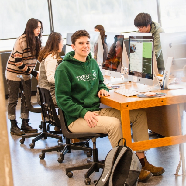 Students at computer lab with one student facing the camera and smiling