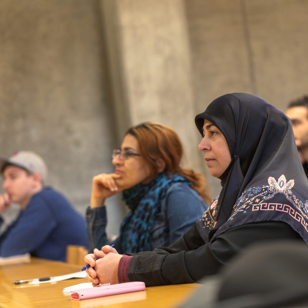 Three students of different ages in a lecture, facing the front of the room