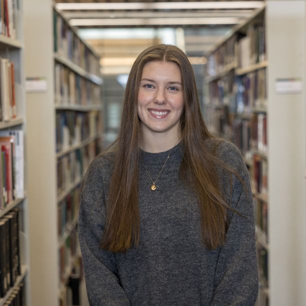 Ainsley, a transfer student, standing between stacks of books at Trent’s Bata Library 