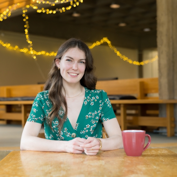Katie, a transfer student, seated at a table in a student space on campus 