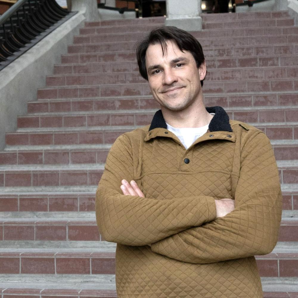 Daniel, a transfer student, standing at the base of a staircase in Trent’s Environmental Science Building 