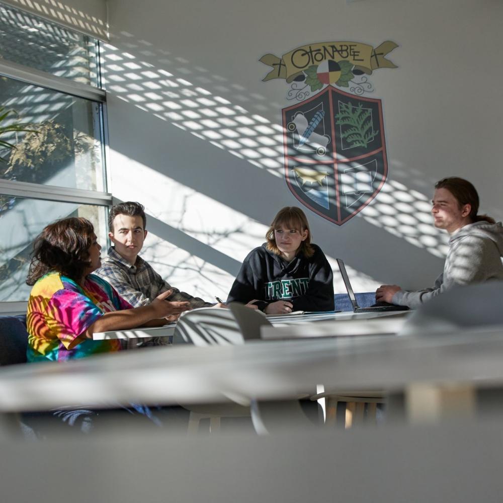 Four students sitting in a common room, chatting together 