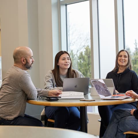 Three people sitting at a table working on computers