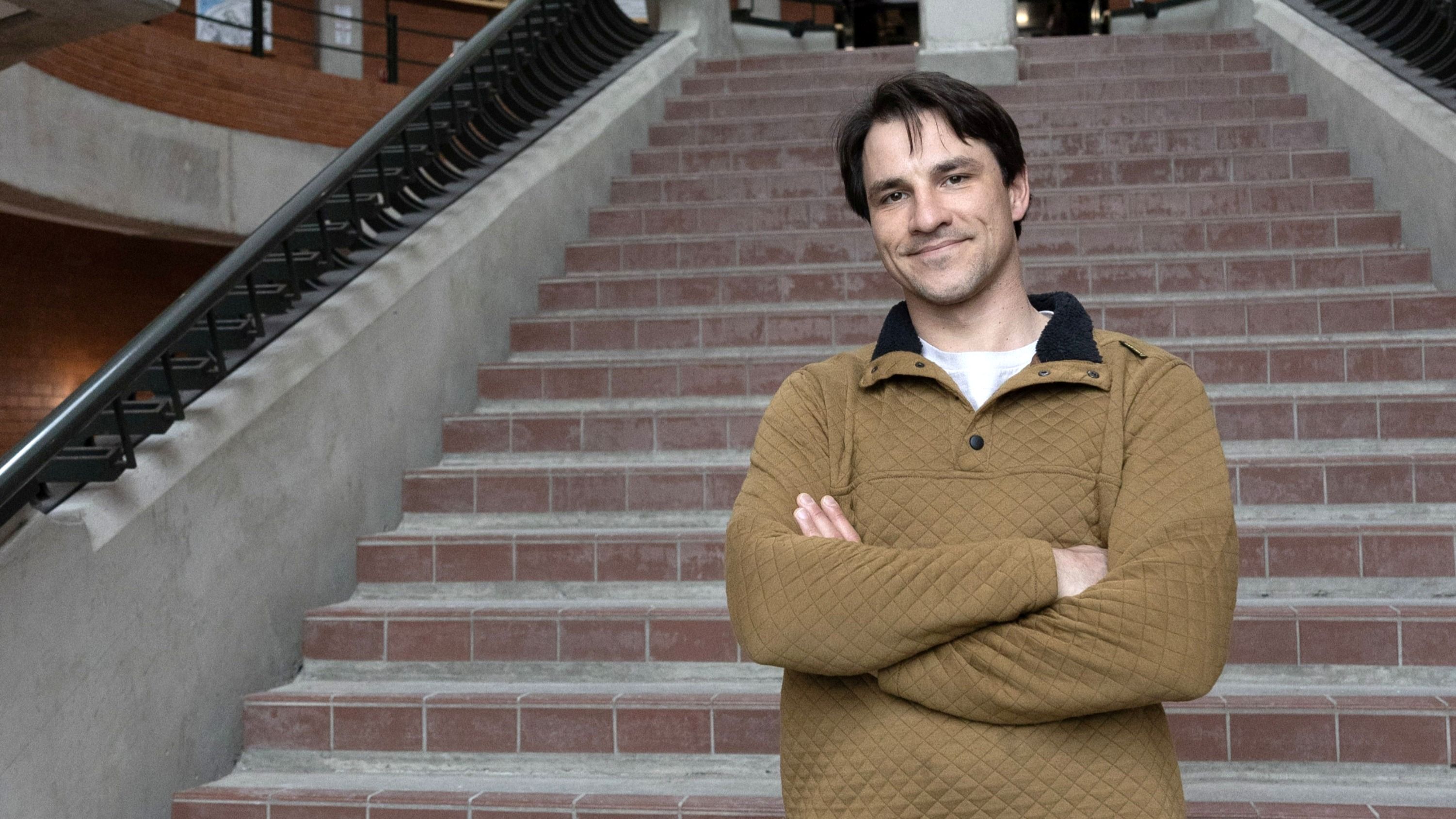 Daniel, a transfer student, standing at the base of a staircase in Trent’s Environmental Science Building