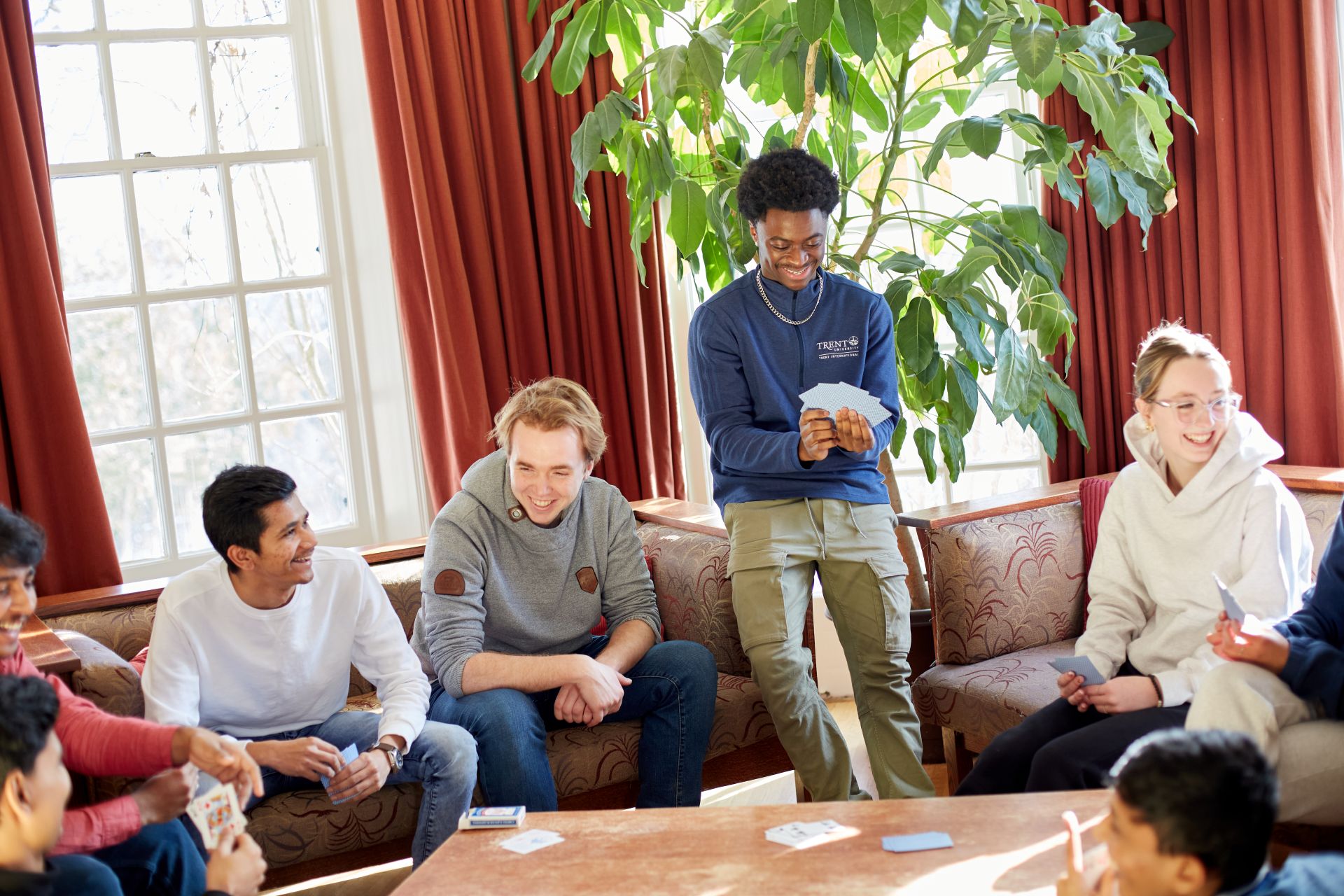 Students sitting in a common room, playing a game of cards