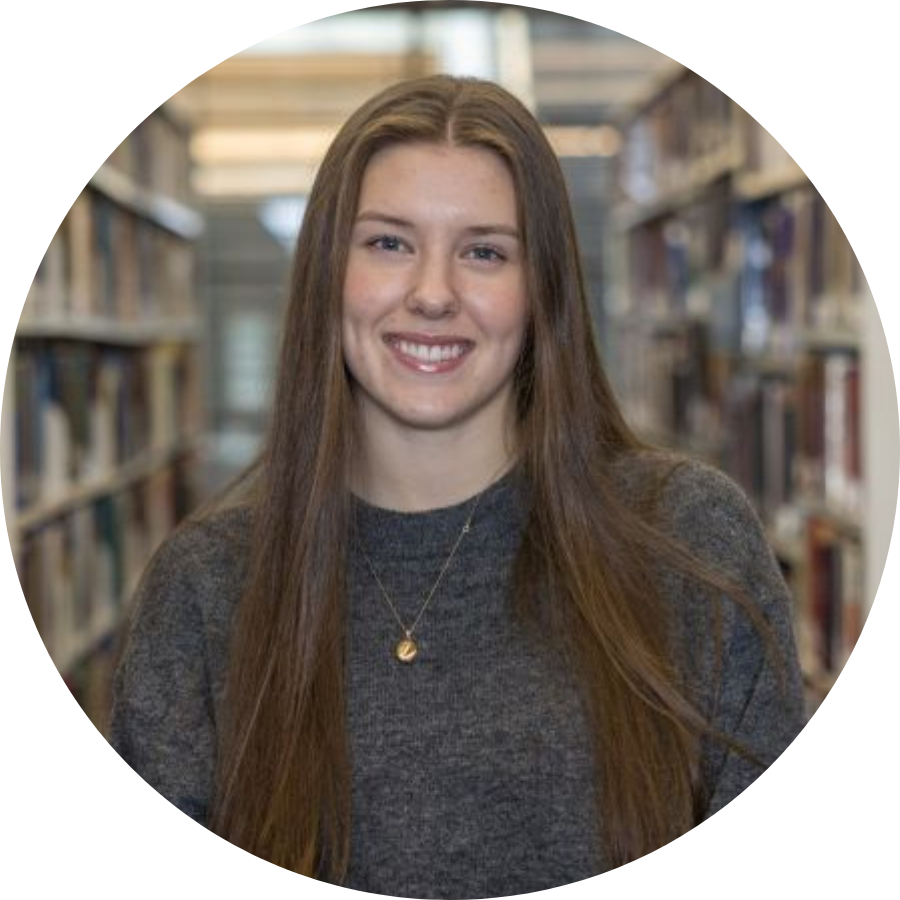 Ainsley, a transfer student, standing between stacks of books at Trent’s Bata Library 