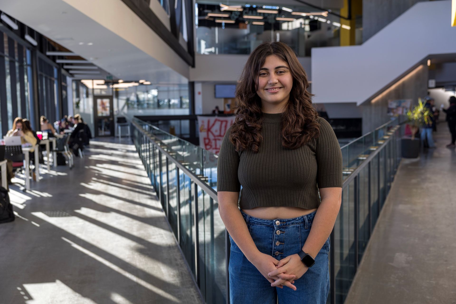 Student smiling at the camera, standing in the Student Centre