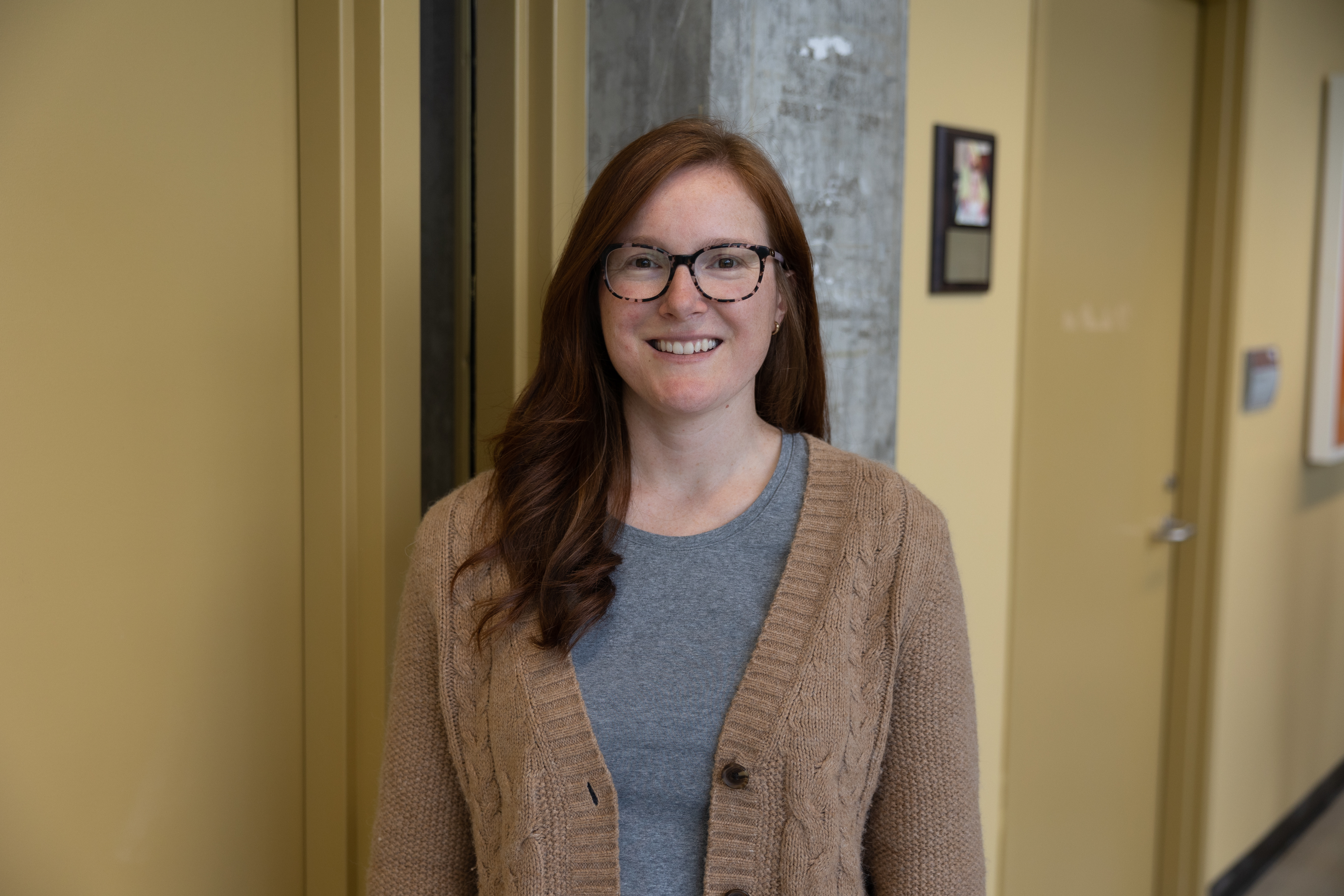 Sylvia smiling and standing in front of a staircase at the Trent library