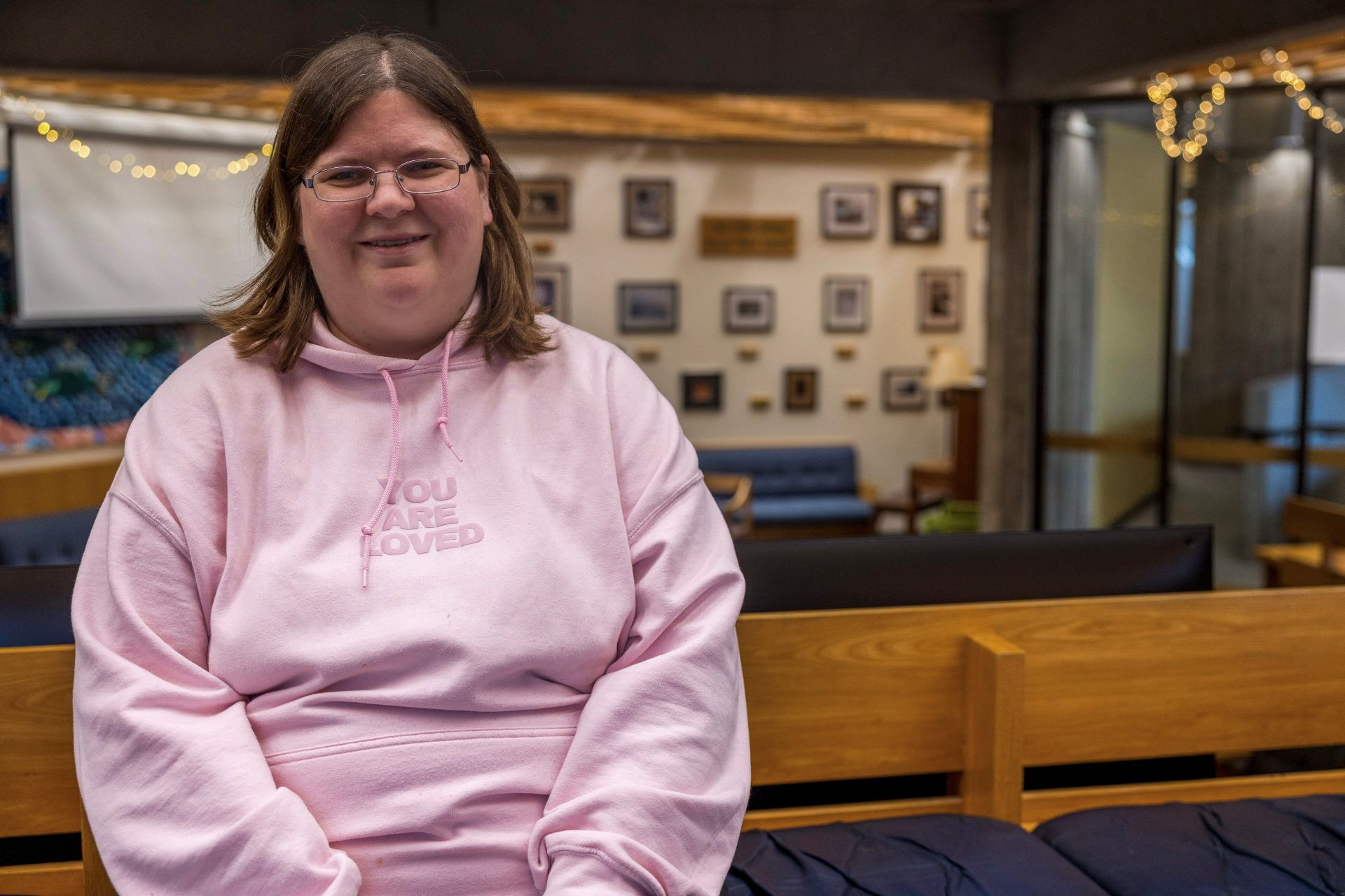 Student in a pink hooded sweater smiling at the camera. 