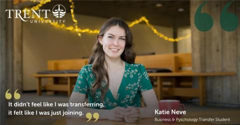 Female student in green, sitting at a table, smiling at the camera