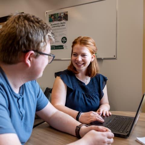 Photo of an advisor helping a student on a computer