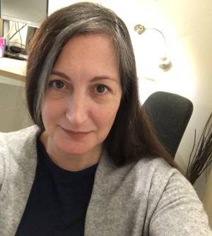 An, with grey sweater on, smiling