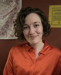 Molly-Claire - woman with brown hair and orange shirt, smiling