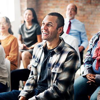 one man sits in the middle of a crowd laughing
