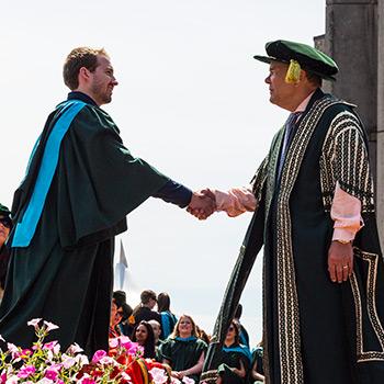 graduate shakes don tapscotts hand on bata podium