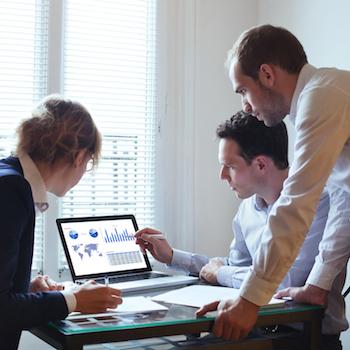 3 students facing a computer and pointing at the screen