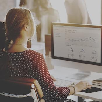 A girl sitting in front of a computer looking at charts and graphs