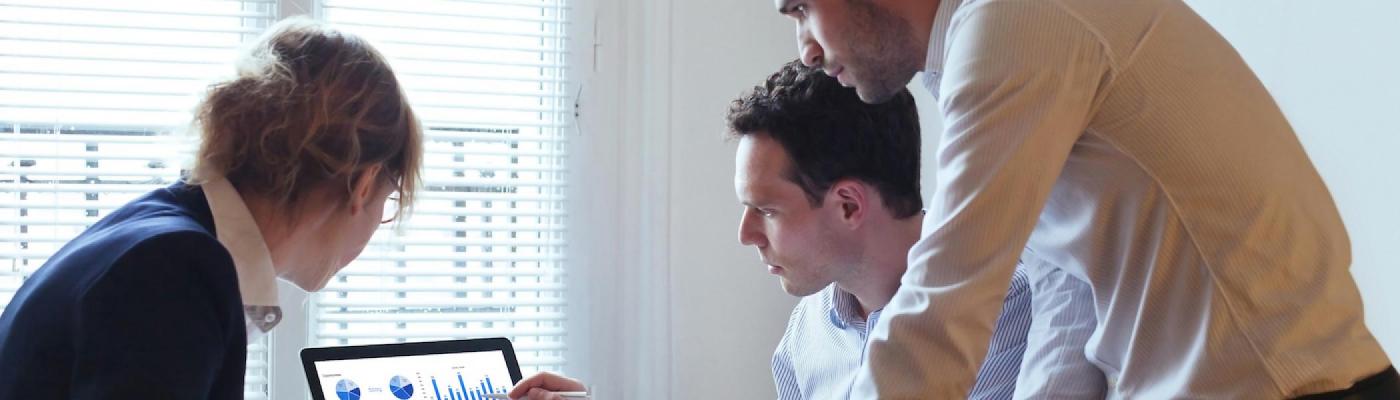 3 students facing a computer and pointing at the screen