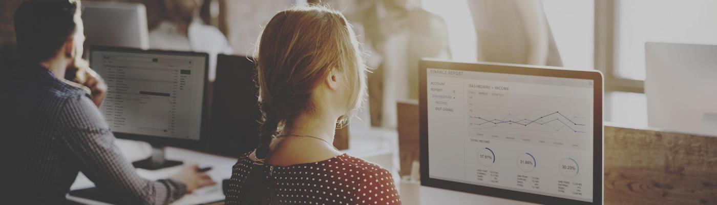 A girl sitting in front of a computer looking at charts and graphs
