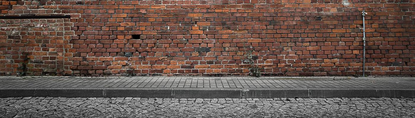 A brick wall with a grey sidewalk supporting it