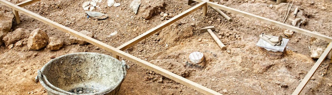 A plot of dirt with digging tools laid out on top of it