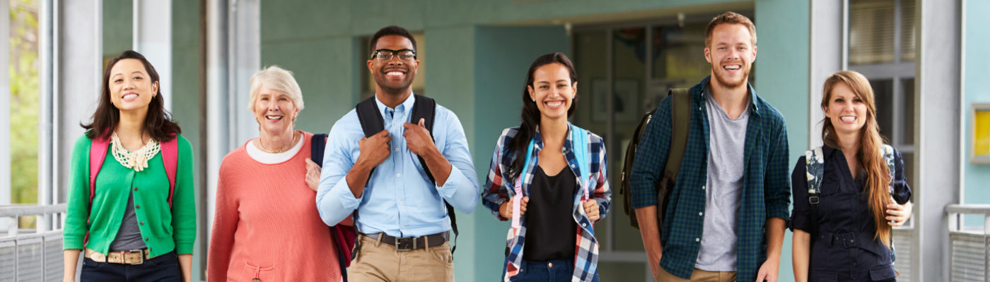 Six smiling teachers wearing backpacks walk together