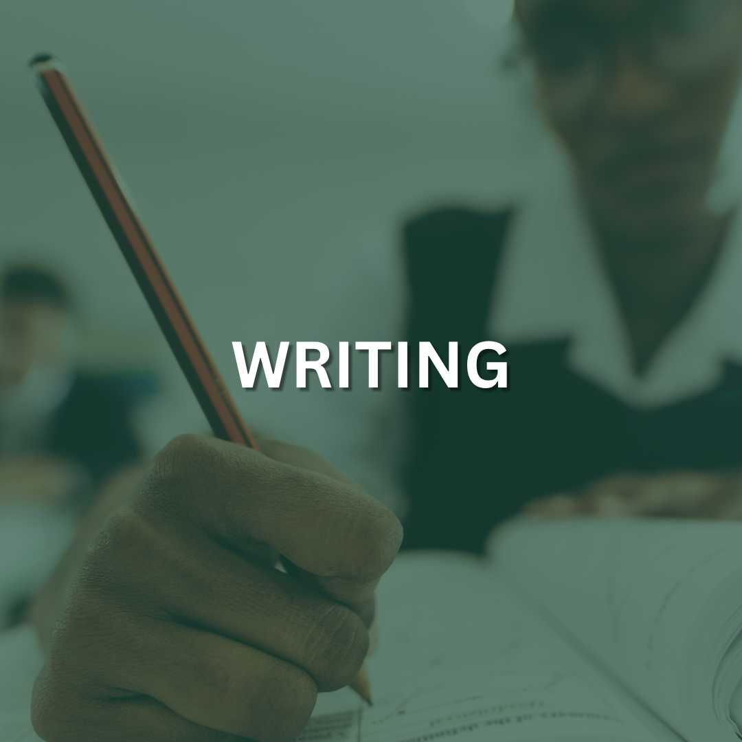 A student is sitting at a desk, holding a pencil and writing into a notebook.