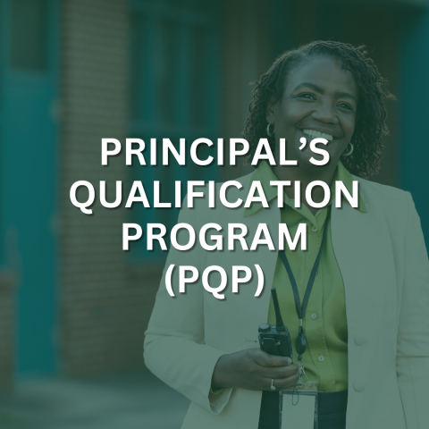 A woman with a lanyard is smiling in front of a school building