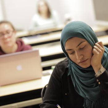A person wearing a Hijab sitting in a class