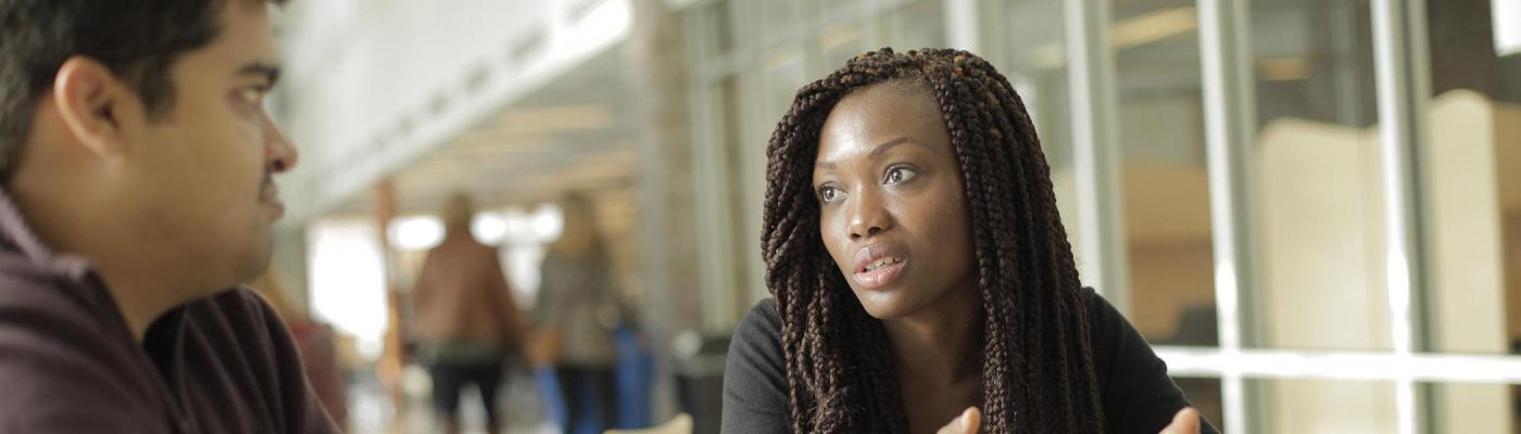 Two students engaging in discussion at at table