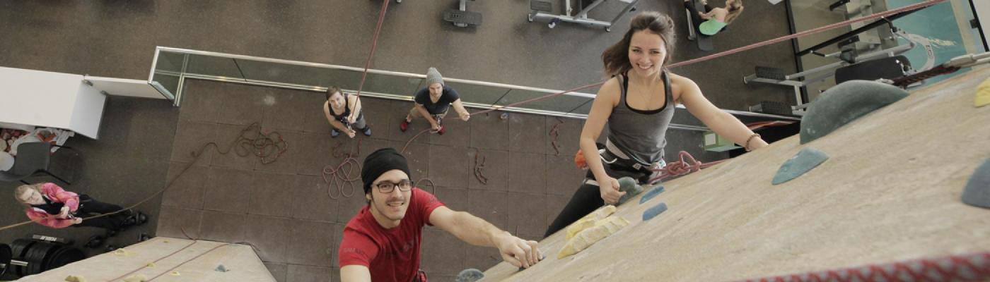 Young man and woman climbing the indoor rock wall
