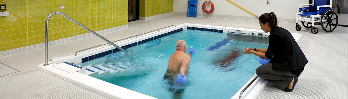 Instructor working with senior in therapy pool