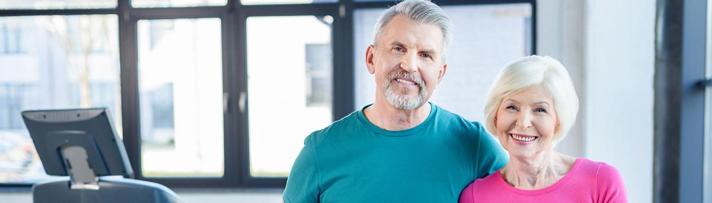 Senior couple holding yoga mats in studio