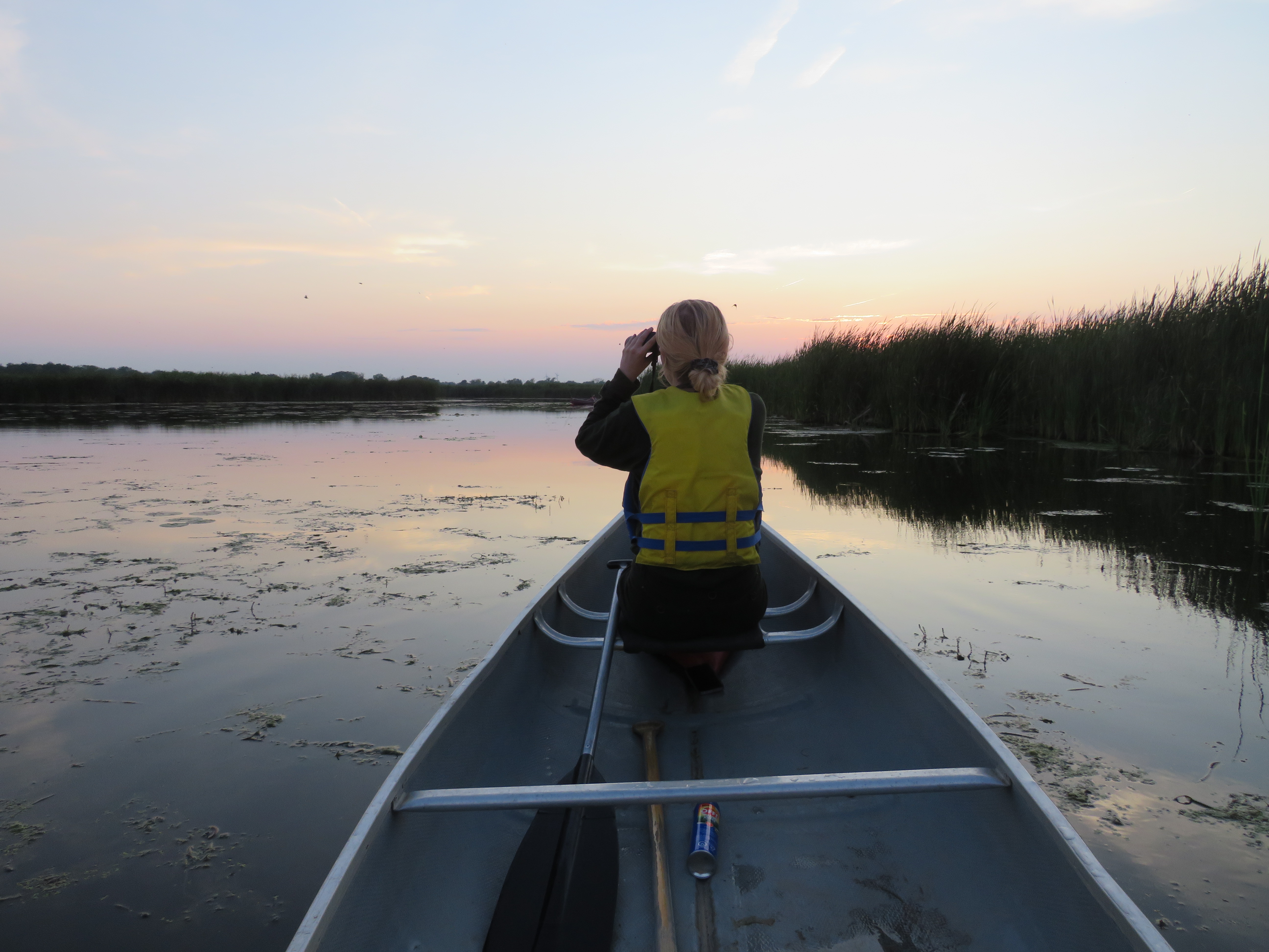 Student in canoe with binoculars