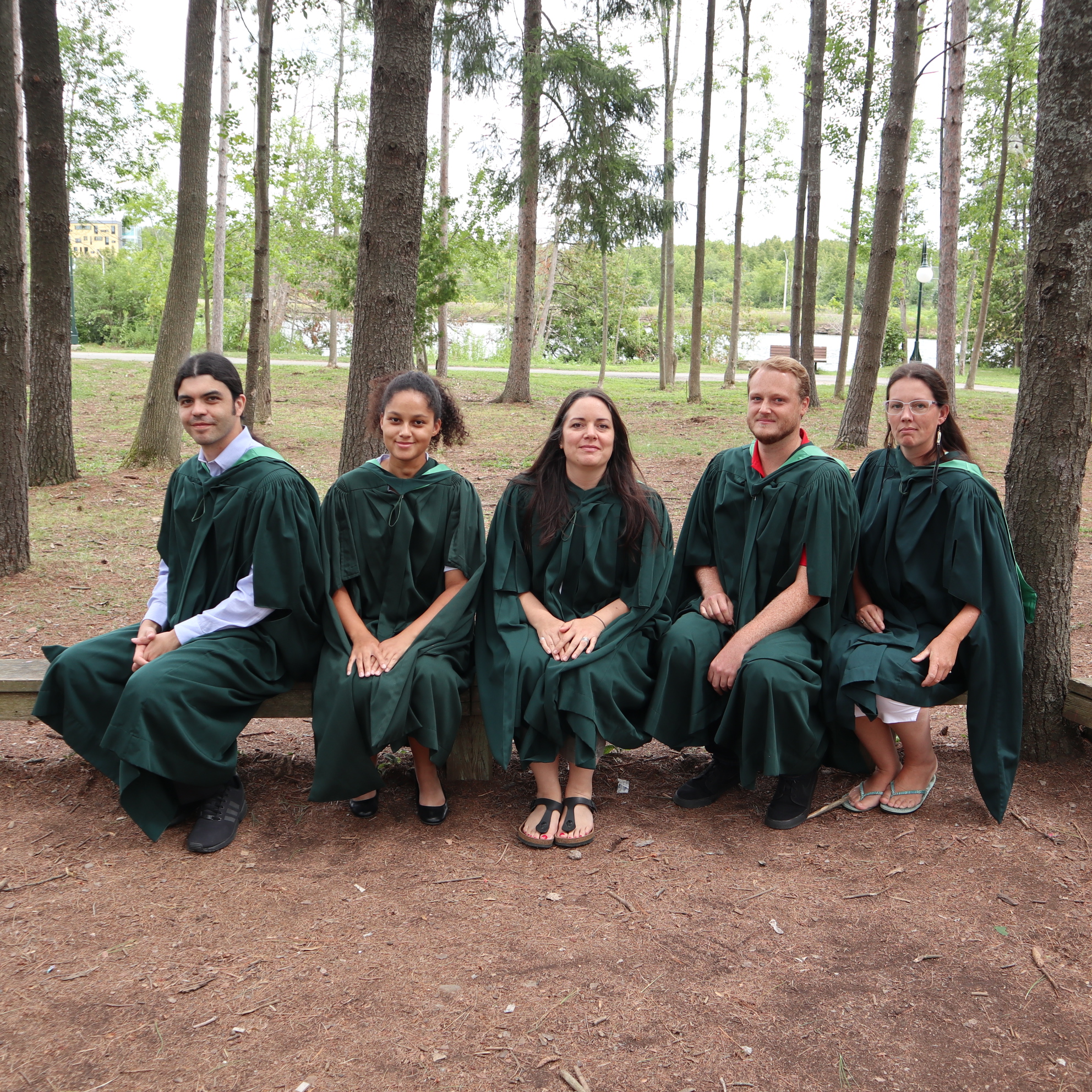 Graduates sitting on log with robes on