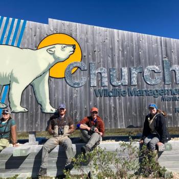 Four students posing in front of a park sign in Churchill, Manitoba