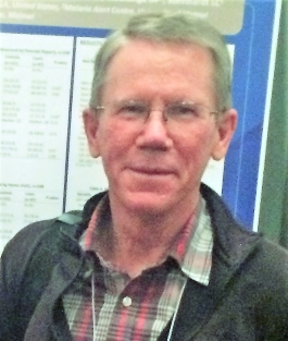 Jim Sutcliffe smiling at the camera, standing in front of an academic poster