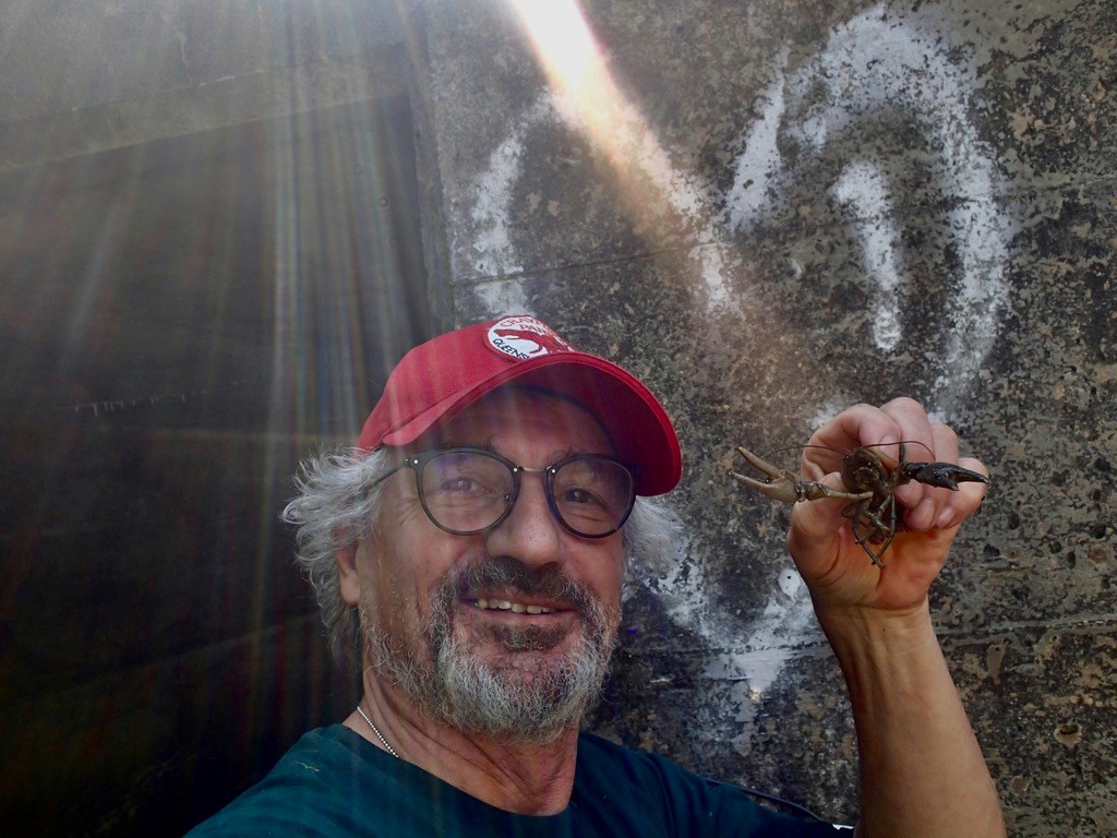 Dr Premek Hamr holding a crayfish infront of a wall