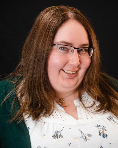 headshot photo of woman smiling with brown hair and glasses