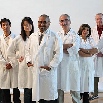 Researchers posing for a group photo in their white lab coats.