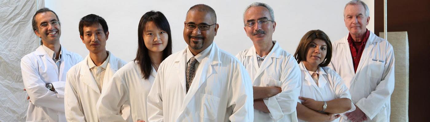 Researchers posing for a group photo in their white lab coats.