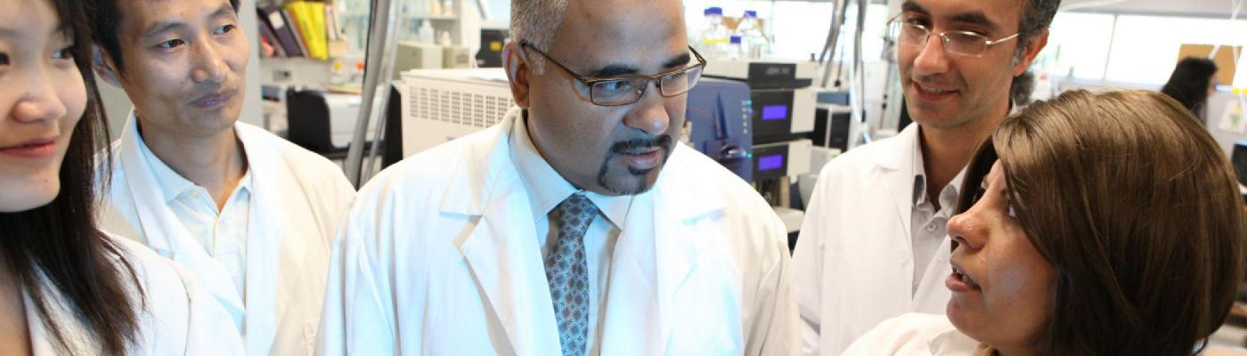 A group of researchers in white lab coats discussing their research.