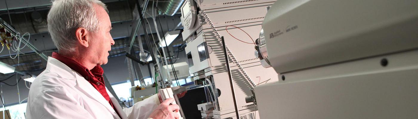Researcher in white lab coat working with an instrument.